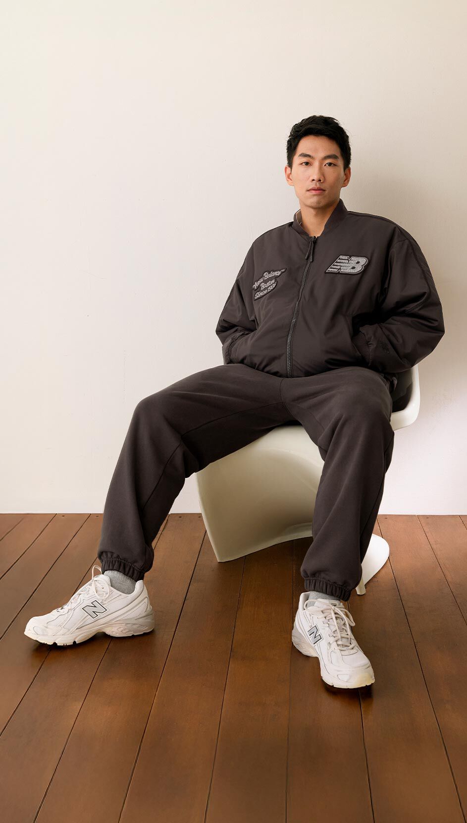 Man sitting on a chair wearing NB Lunar New Year apparel and footwear