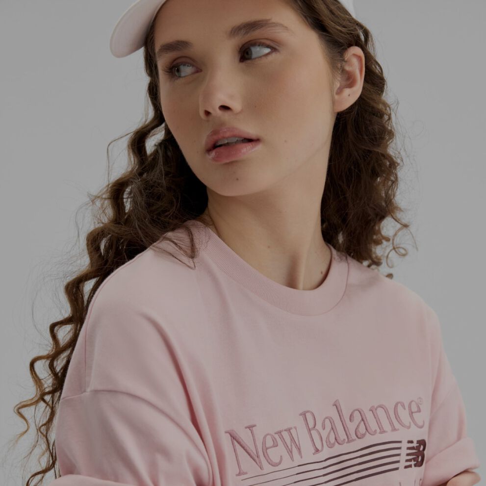 Gros plan d'une femme portant une chemise rose p&acirc;le et un chapeau.