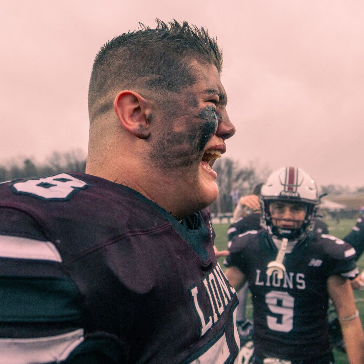 Young man yelling out on the football field.