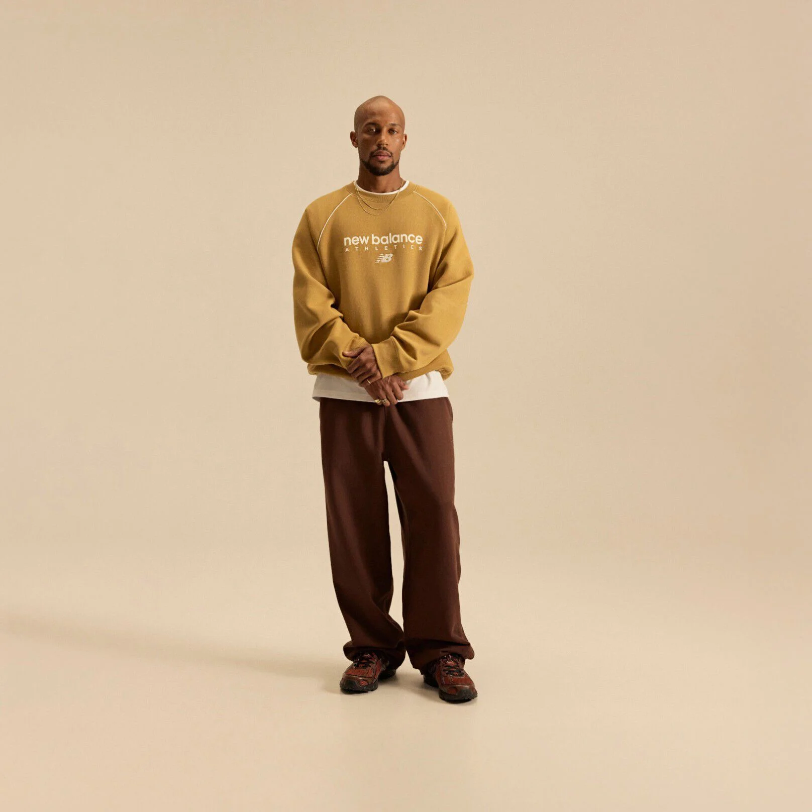 Image of Brian Reid in a New Balance outfit with a pale brown top in front of a beige background.