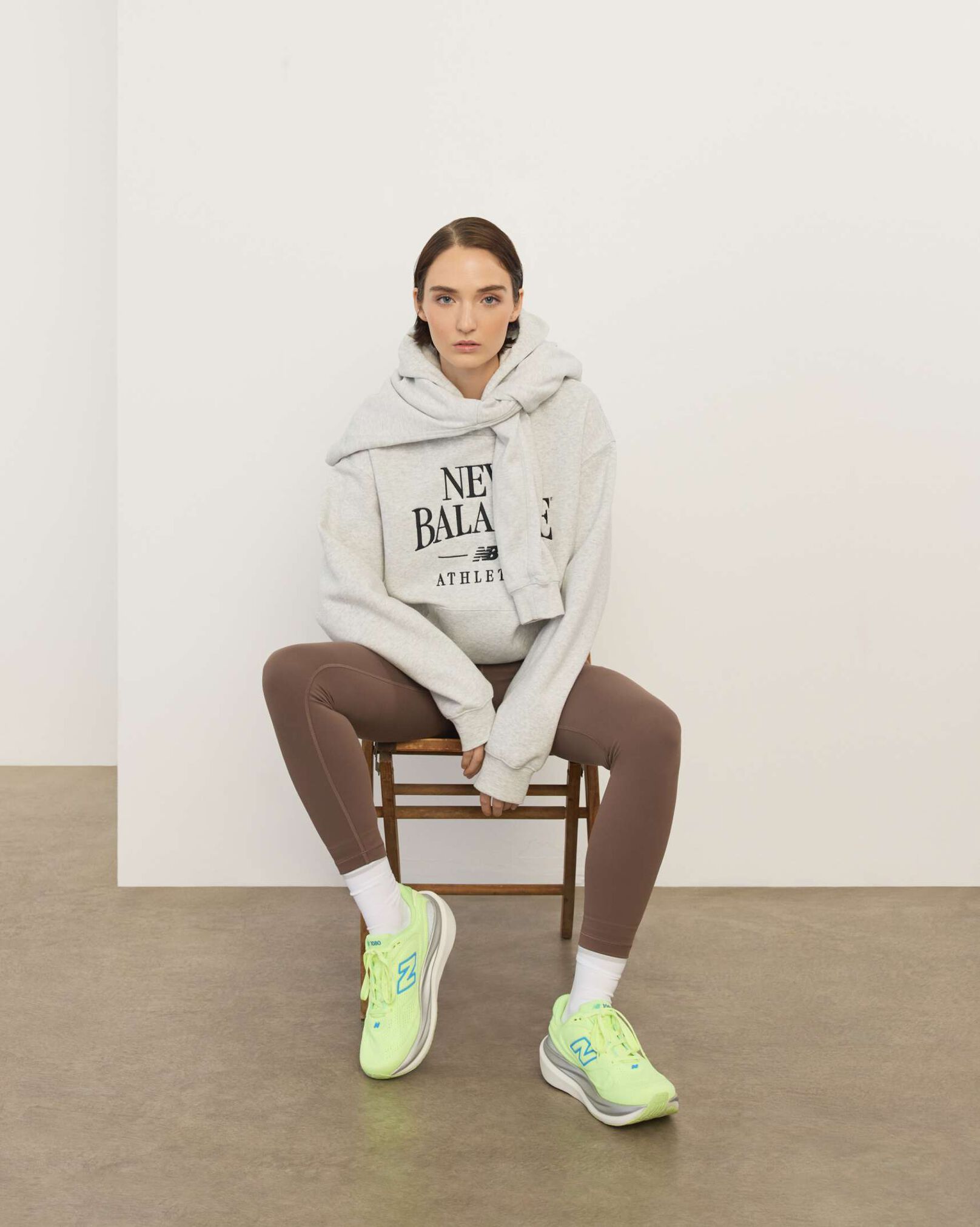 A woman sitting in a chair in front a white wall.
