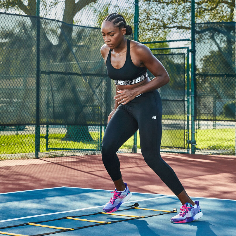 Coco Gauff training on a tennis court in a black matching set and multi-colored FuelCell Shift TRs