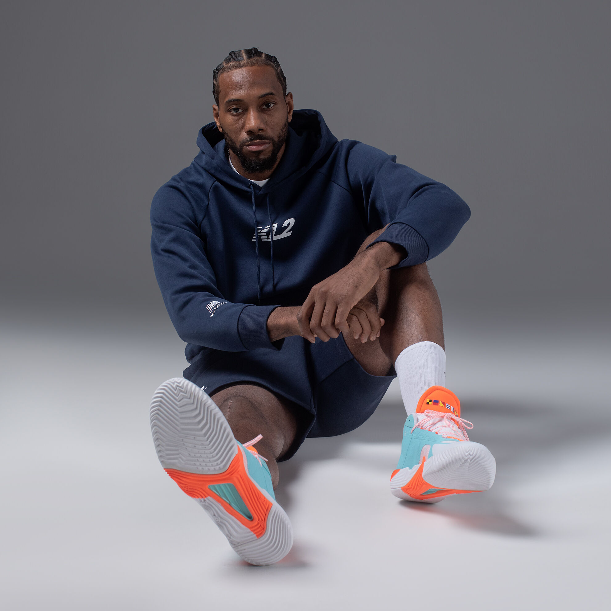 Kawhi Leonard sitting on the floor in a black hoodie and his signature shoe.