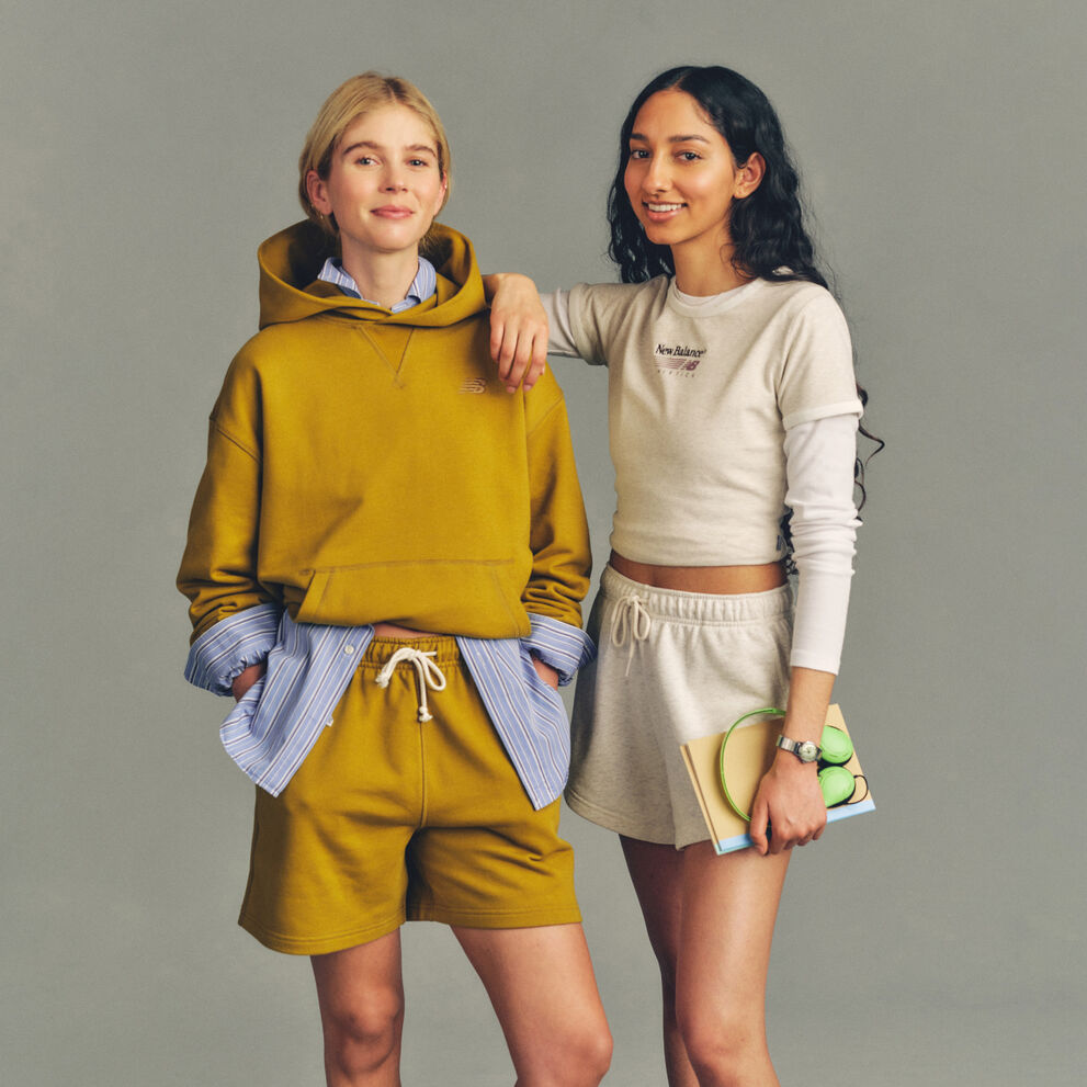 Studio image of two people positioned against a plain light gray background, styled in casual athletic apparel.
