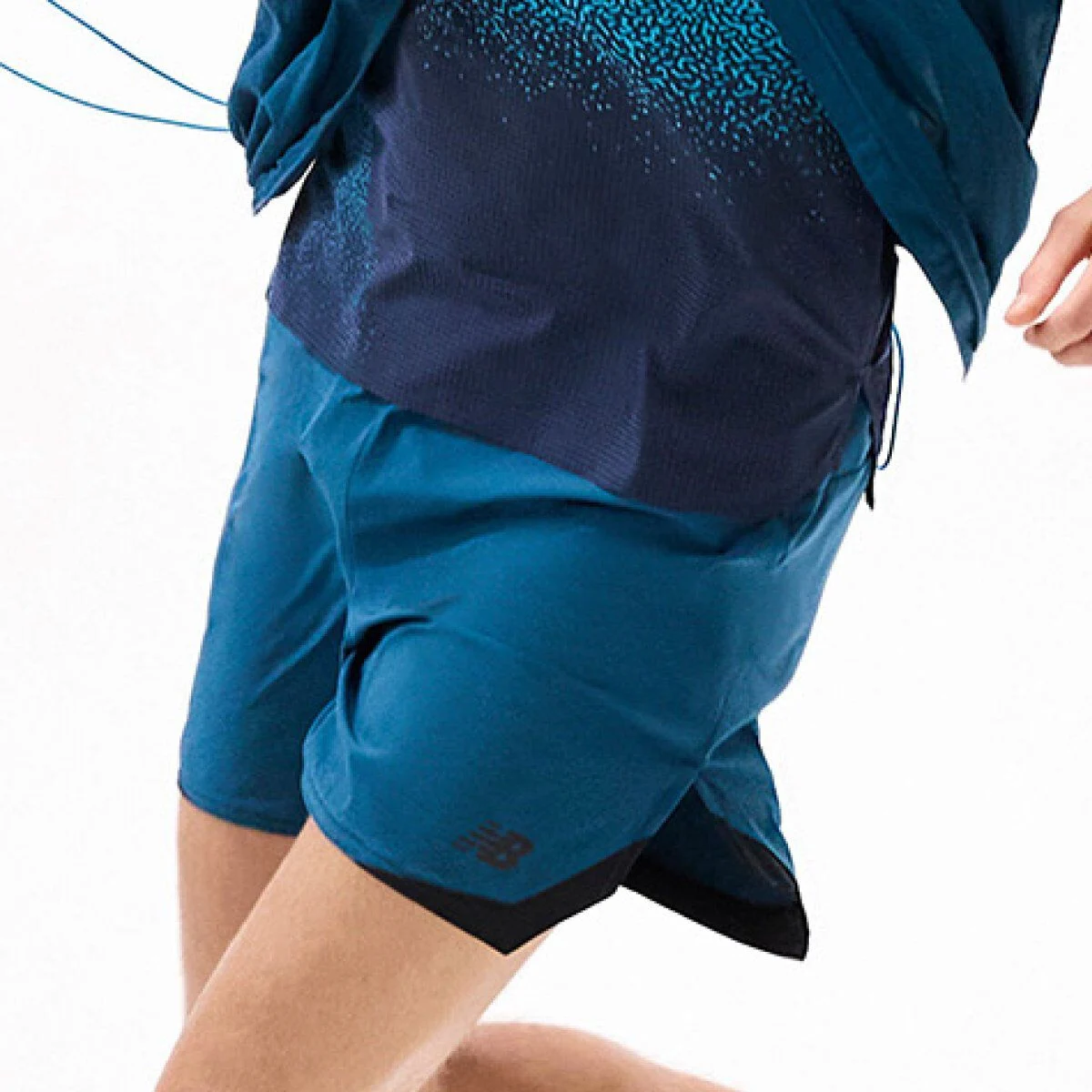 Close-up of teal running shorts in motion paired with a layered performance top against a white background. 