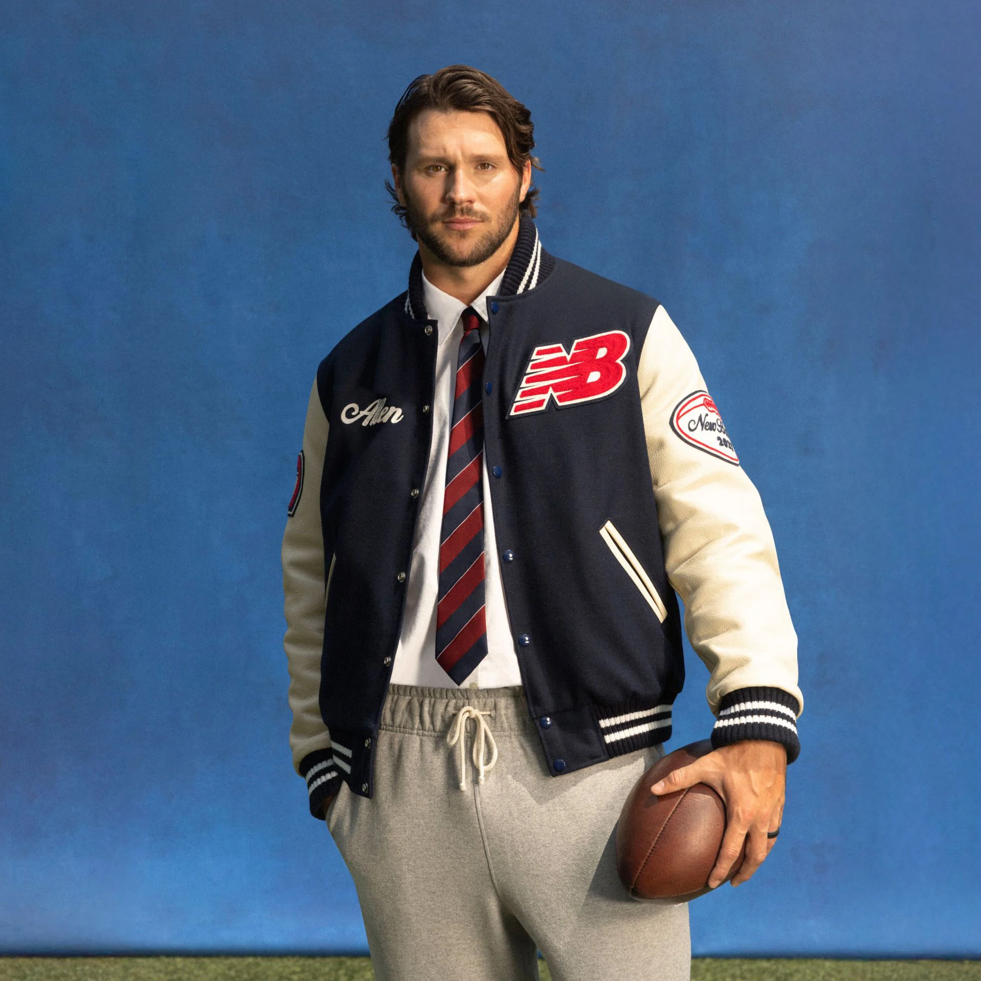 Young athlete standing on a field with a blue background wearing a custom jacket.