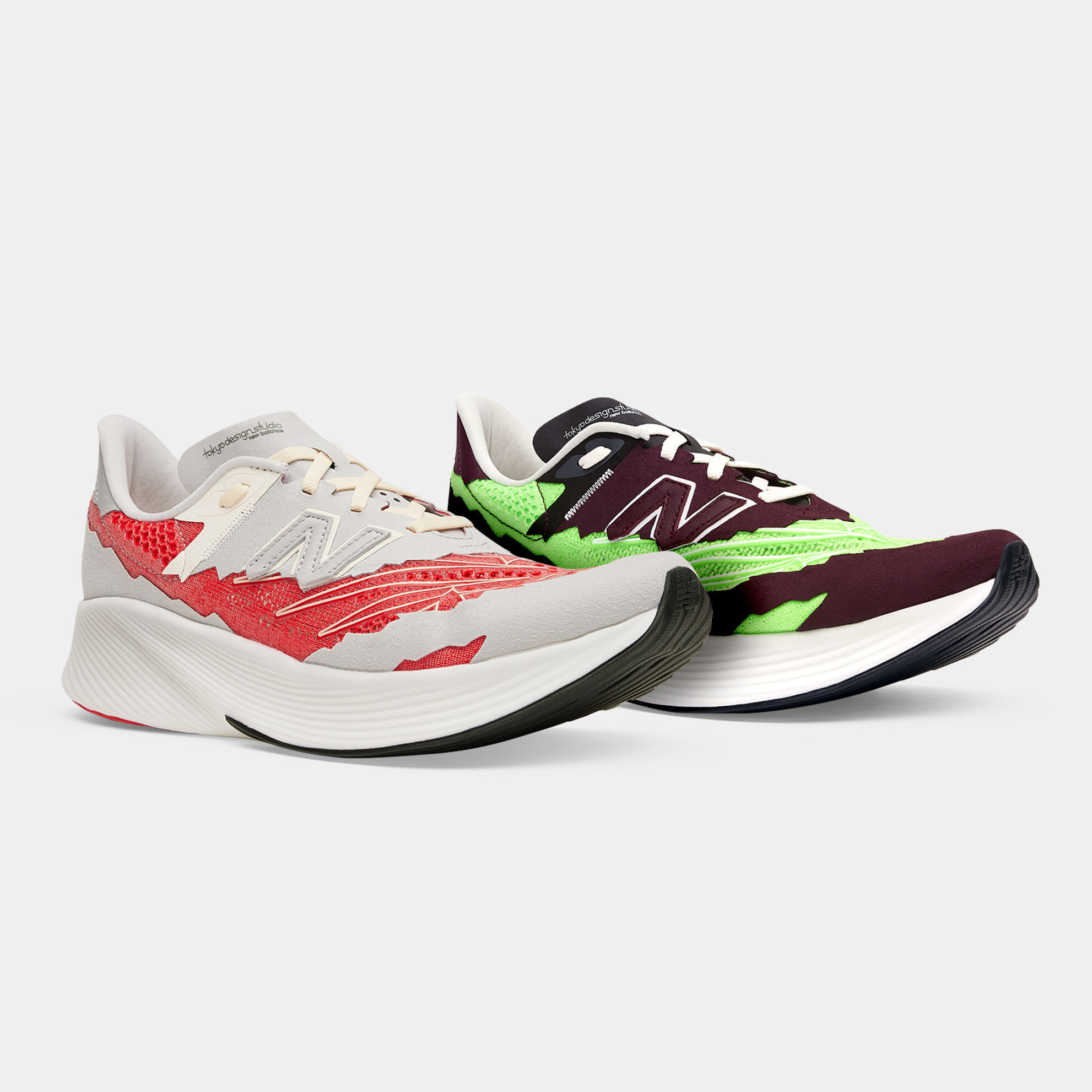 Angle avant 3/4 de deux chaussures de course NB Stone Island Tokyo Design Studio FuelCell RC Elite assises sur un fond gris clair. L’un est gris clair avec des accents rouges et l’autre est brun rougeâtre foncé avec des accents vert lime
