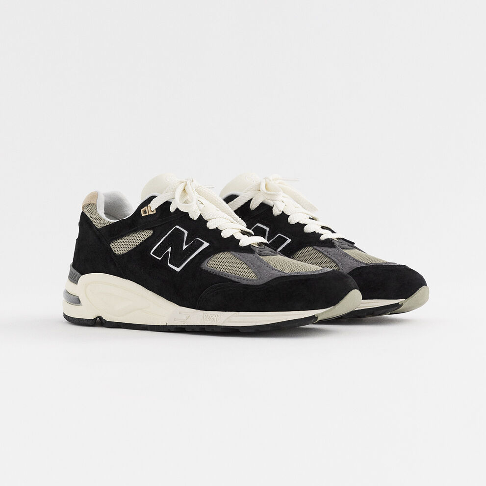 Pair of black and cream MADE in USA 990v2 sitting on a grey studio environment.