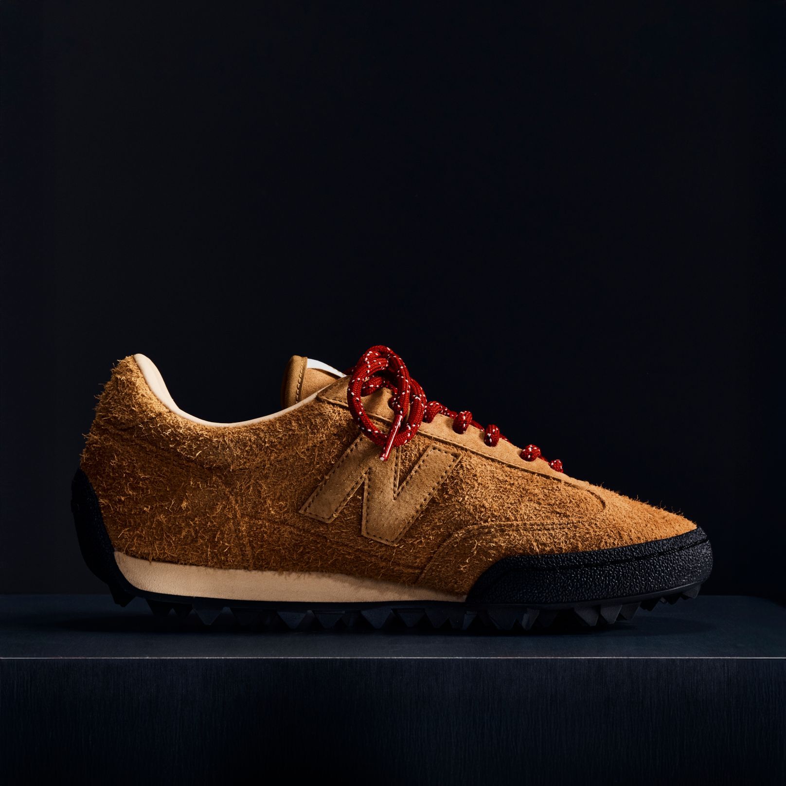 A brown suede Gator Run shoe on a black background.