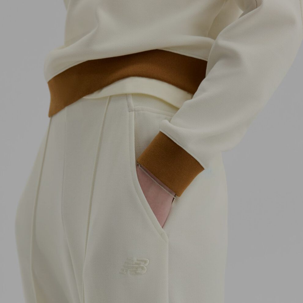 Gros plan de quelqu&rsquo;un portant un pantalon New Balance cr&egrave;me et brun sur un fond blanc.