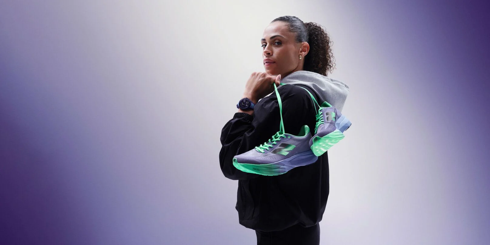 Sydney McLaughlin-Levrone holding a pair of shoes over her shoulder and looking towards the viewer. 