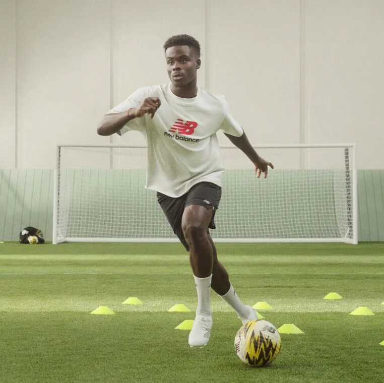 Soccer player dribbling the ball through cones