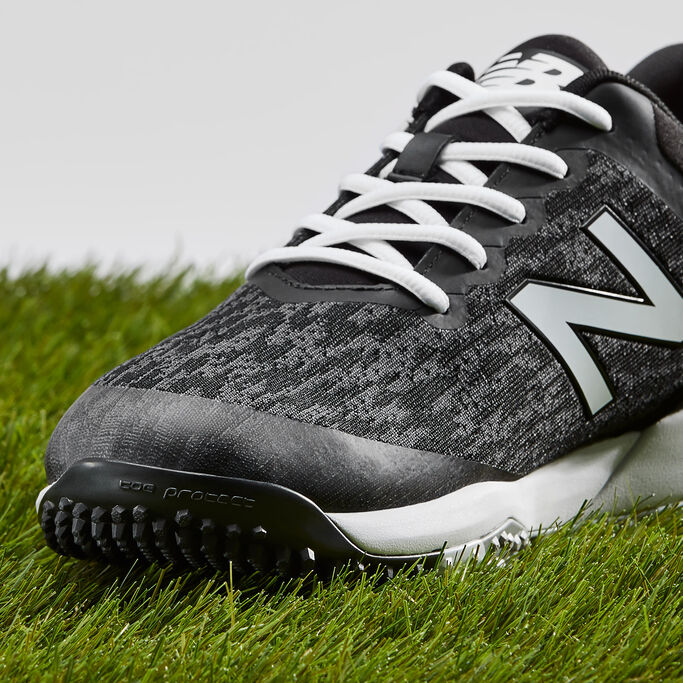 Close up front view of the black 4040v5 Turf shoe sitting on grass