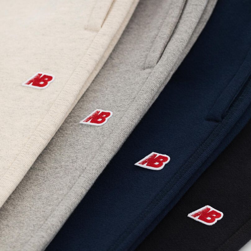 Gros plan d’une pile de pantalons de survêtement MADE in USA, montrant le logo New Balance sur chaque.