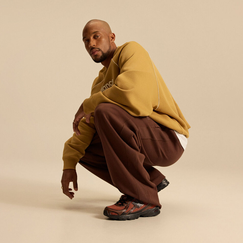 Image of Brian Reid in a New Balance outfit with a pale brown top in front of a beige background.