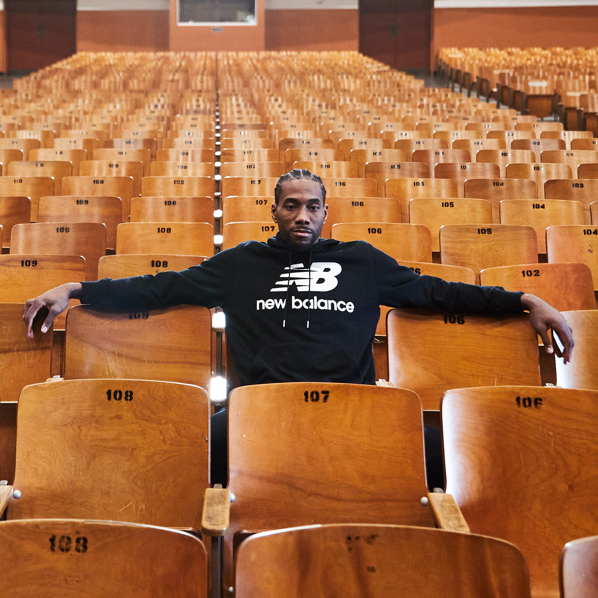Kawhi Leonard sitting in the stands of an auditorium  