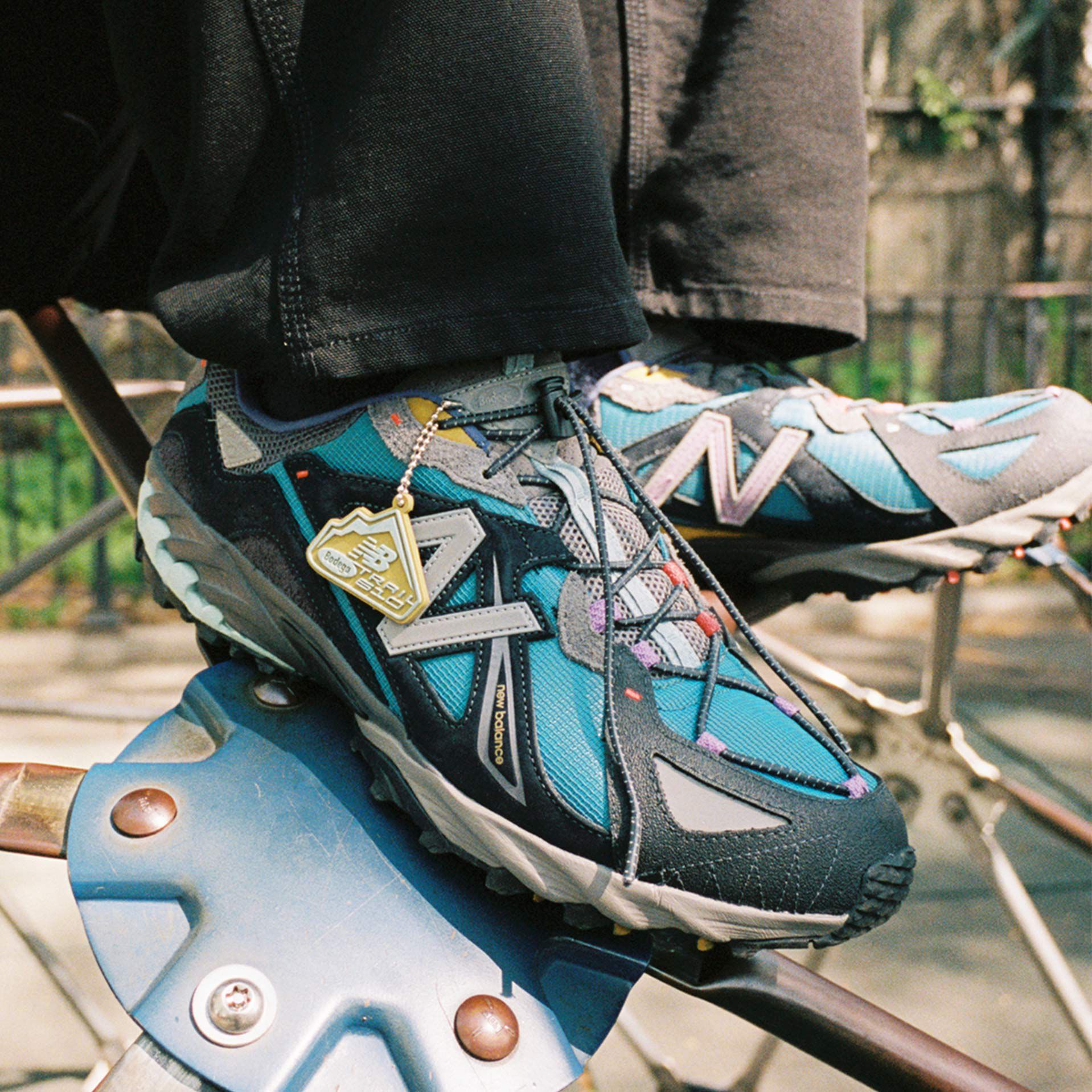 Ankle down shot of a person wearing Bodega 610 shoes while sitting on playground equipment.