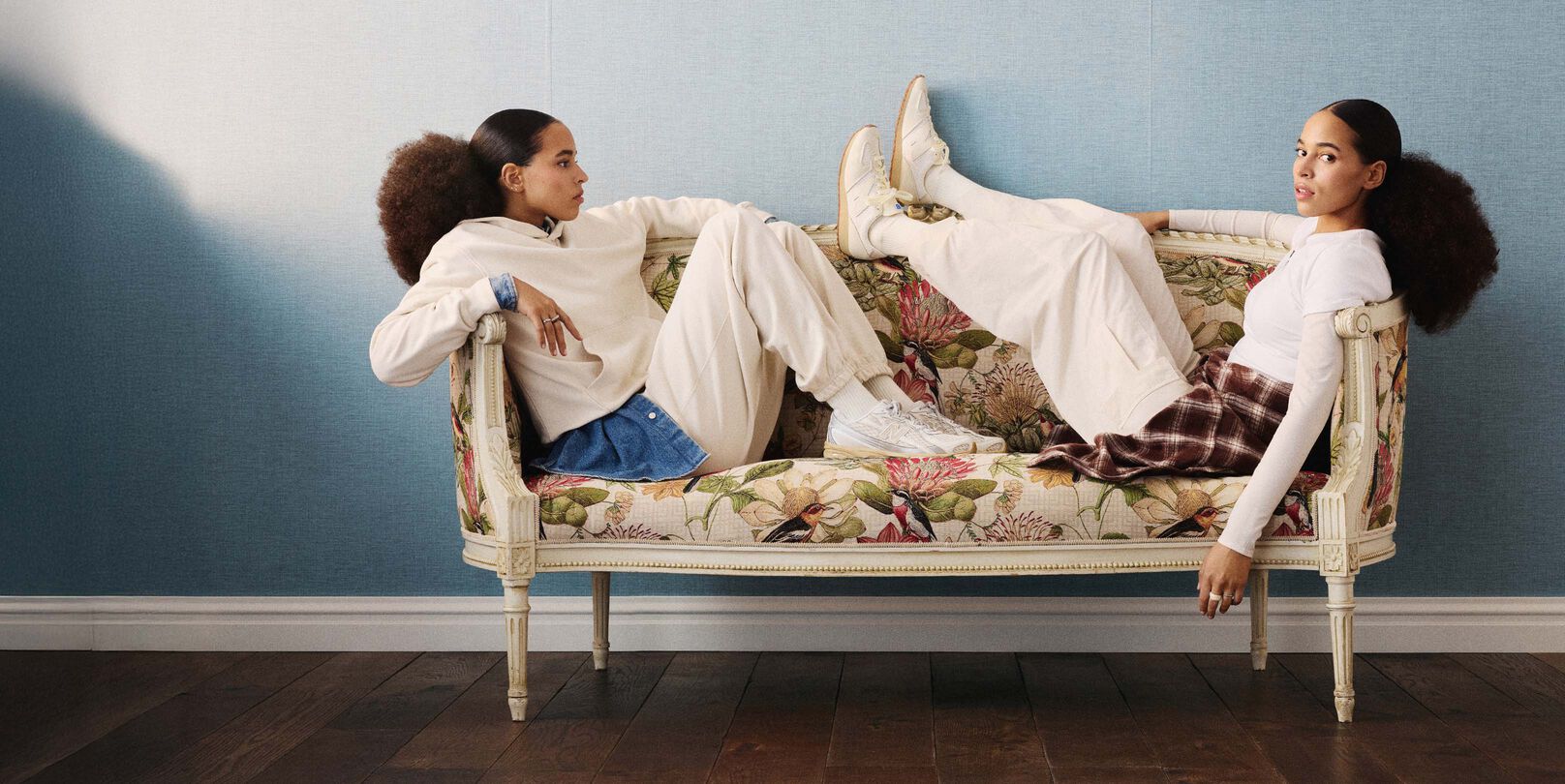 Two models sitting on a couch wearing the 471 and 740 shoes.