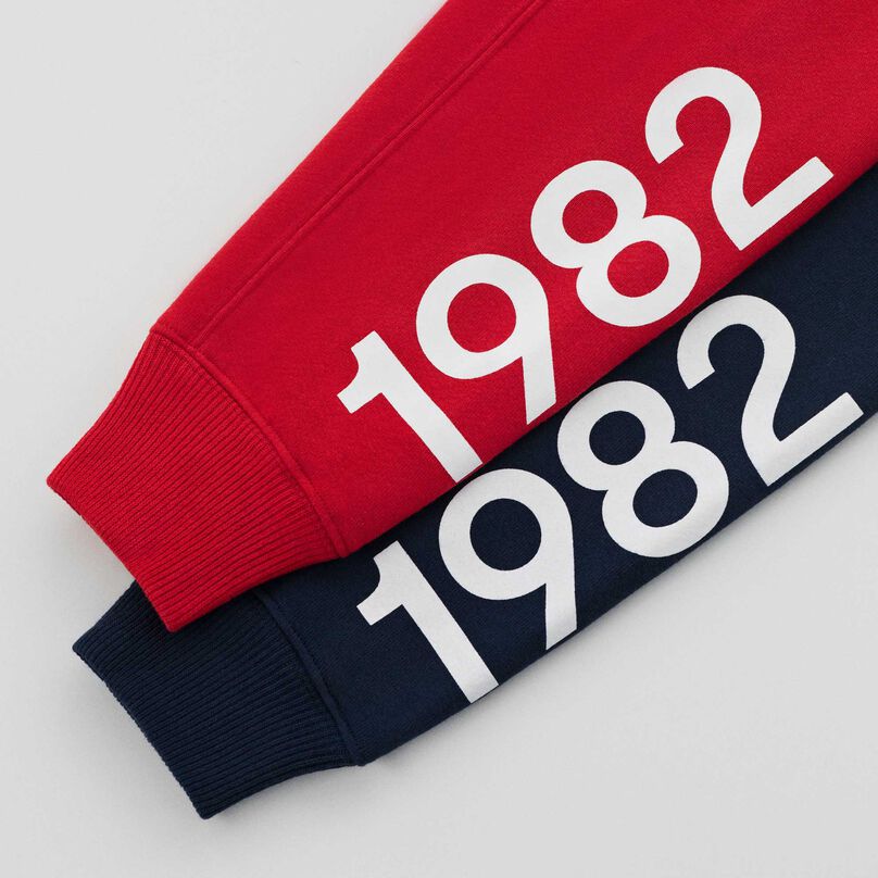 Détails des manches du sweat à capuche MADE in USA rouge et bleu marine, révélant l’année 1982 imprimée.