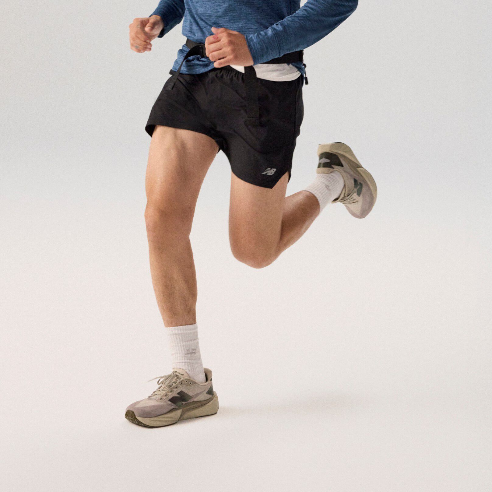 Young man running wearing a navy jacket on a grey background.