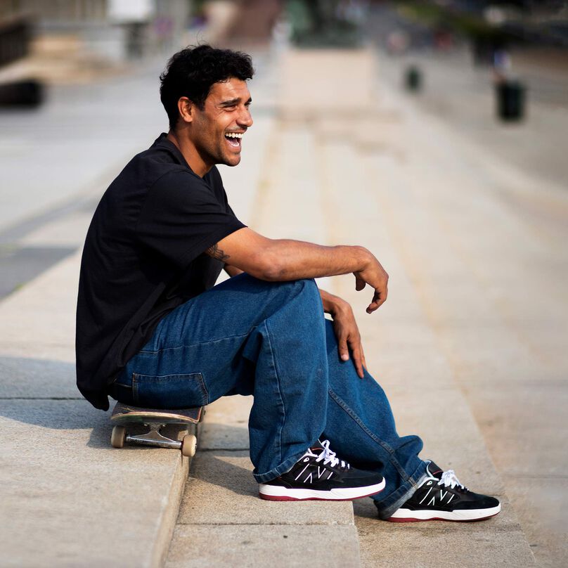 Tiago Lemos assis sur son skate, sur des marches à l’extérieur, et portant des chaussures 808 Numeric.