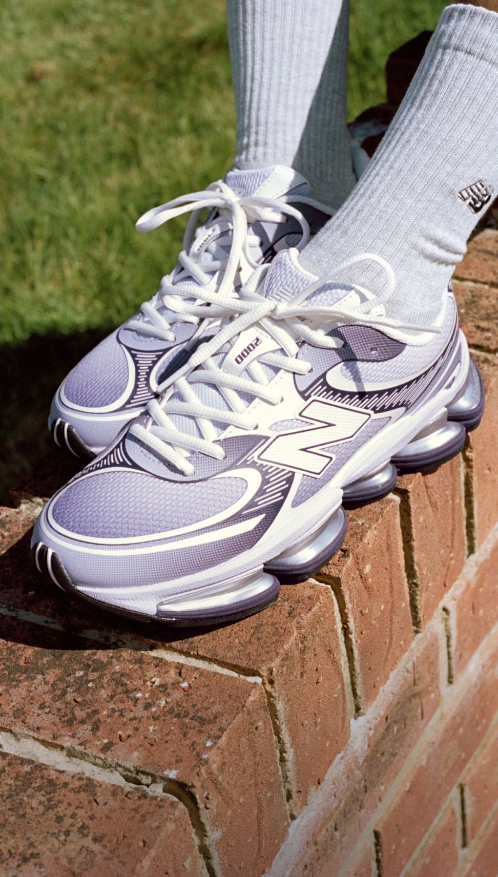 Gros plan de quelqu&rsquo;un portant des baskets New Balance sur fond en brique.