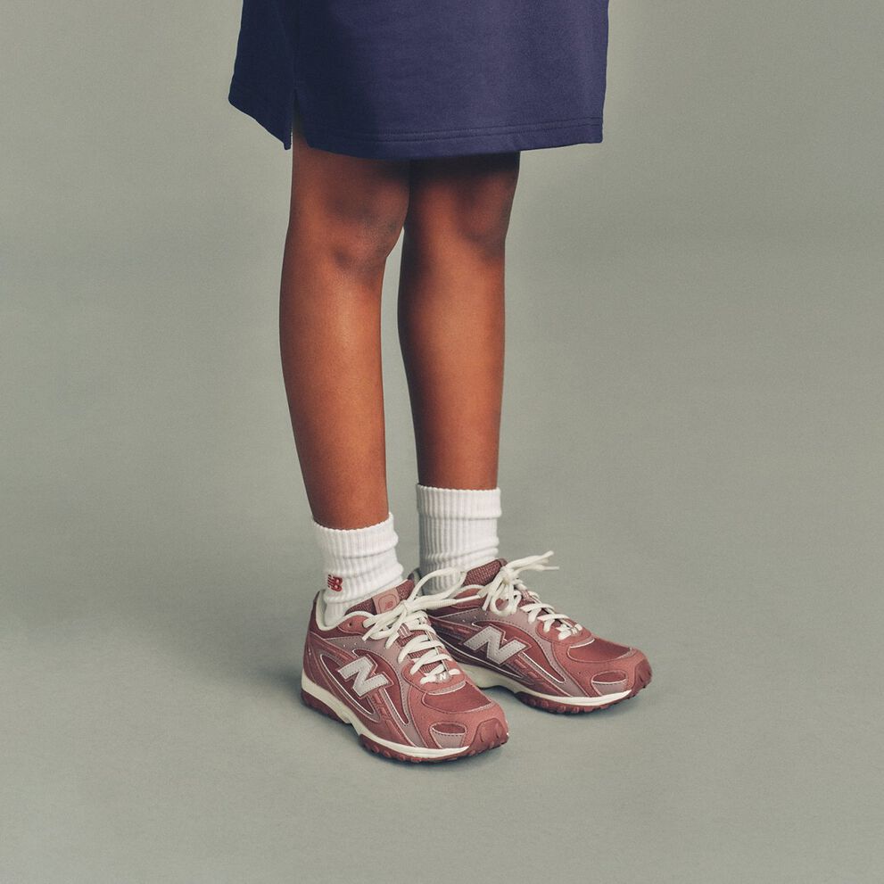 L'enfant porte un haut bleu marine qui lui arrive &agrave; mi-cuisse et des bas blancs &agrave; c&ocirc;tes, orn&eacute;s d'un petit logo &laquo;&nbsp;NB&nbsp;&raquo; rouge pr&egrave;s du bord.