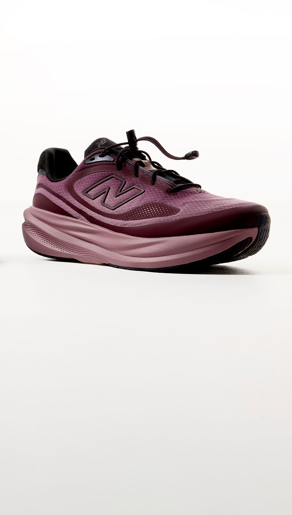 A plum colored shoe sitting against a grey studio backdrop.