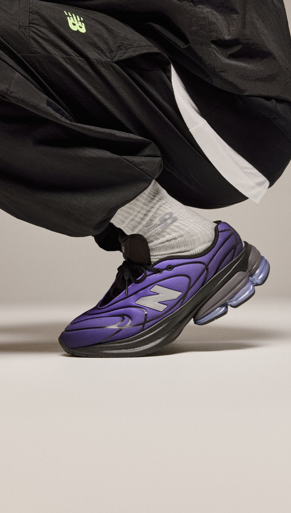 Plan des genoux vers le bas d&rsquo;un homme portant des chaussures violettes sur un fond beige. 