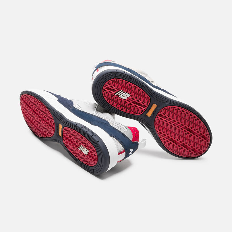 A pair of 808 Numeric shoes with the red soles facing the camera.