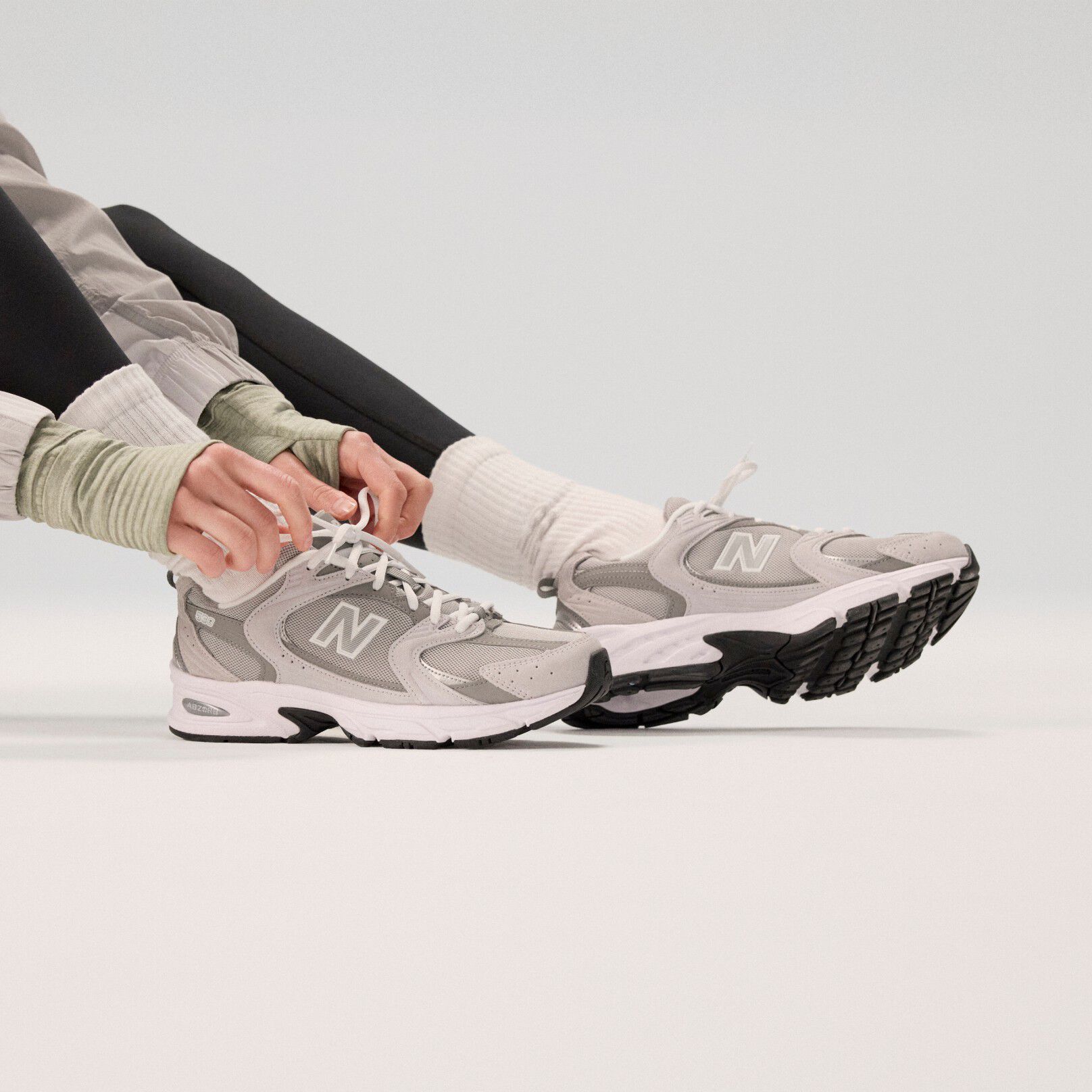 Mannequin portant des chaussures gris pâle sur fond gris.