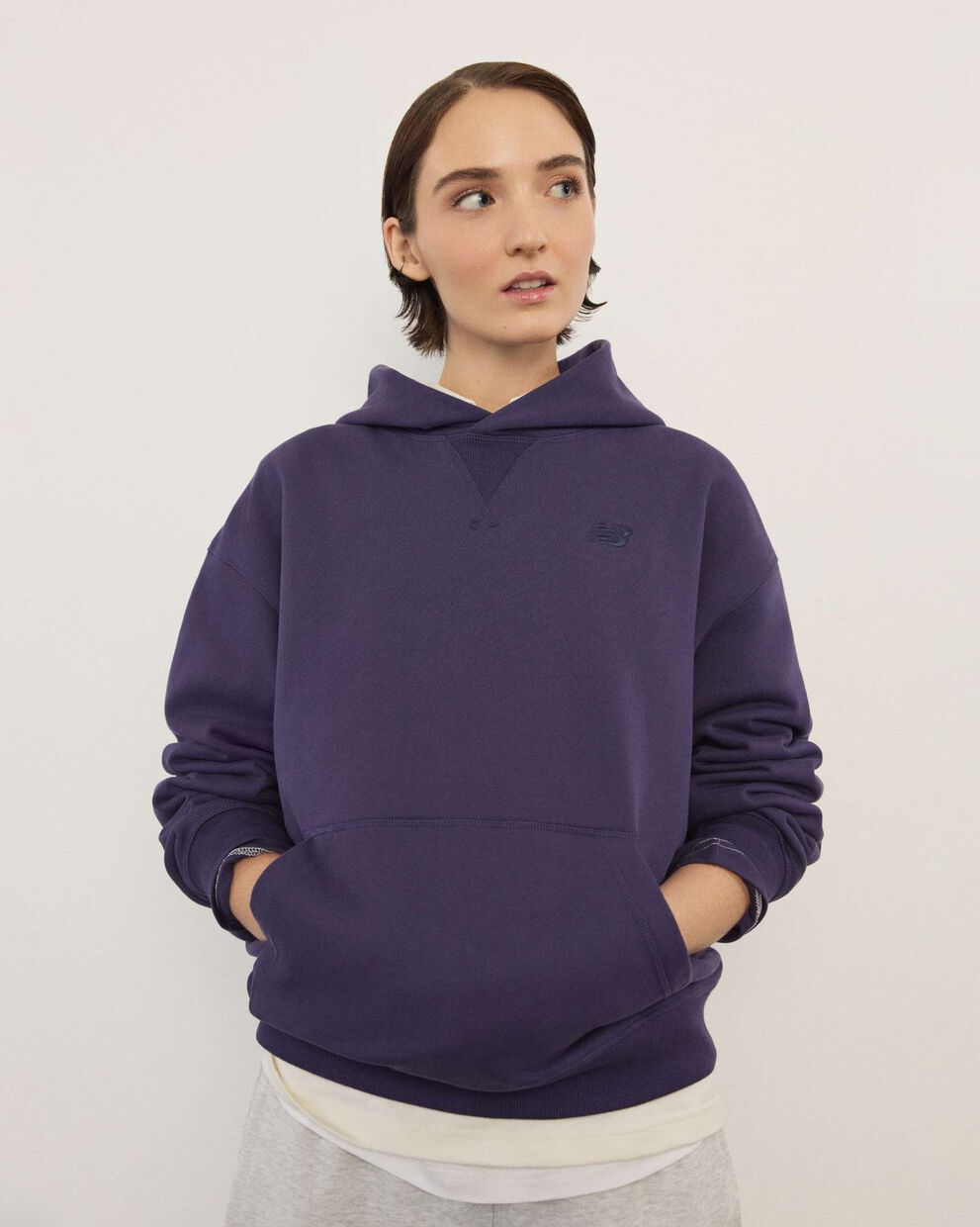 A woman standing in front a white wall.