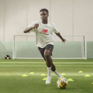 Soccer player dribbling the ball through cones