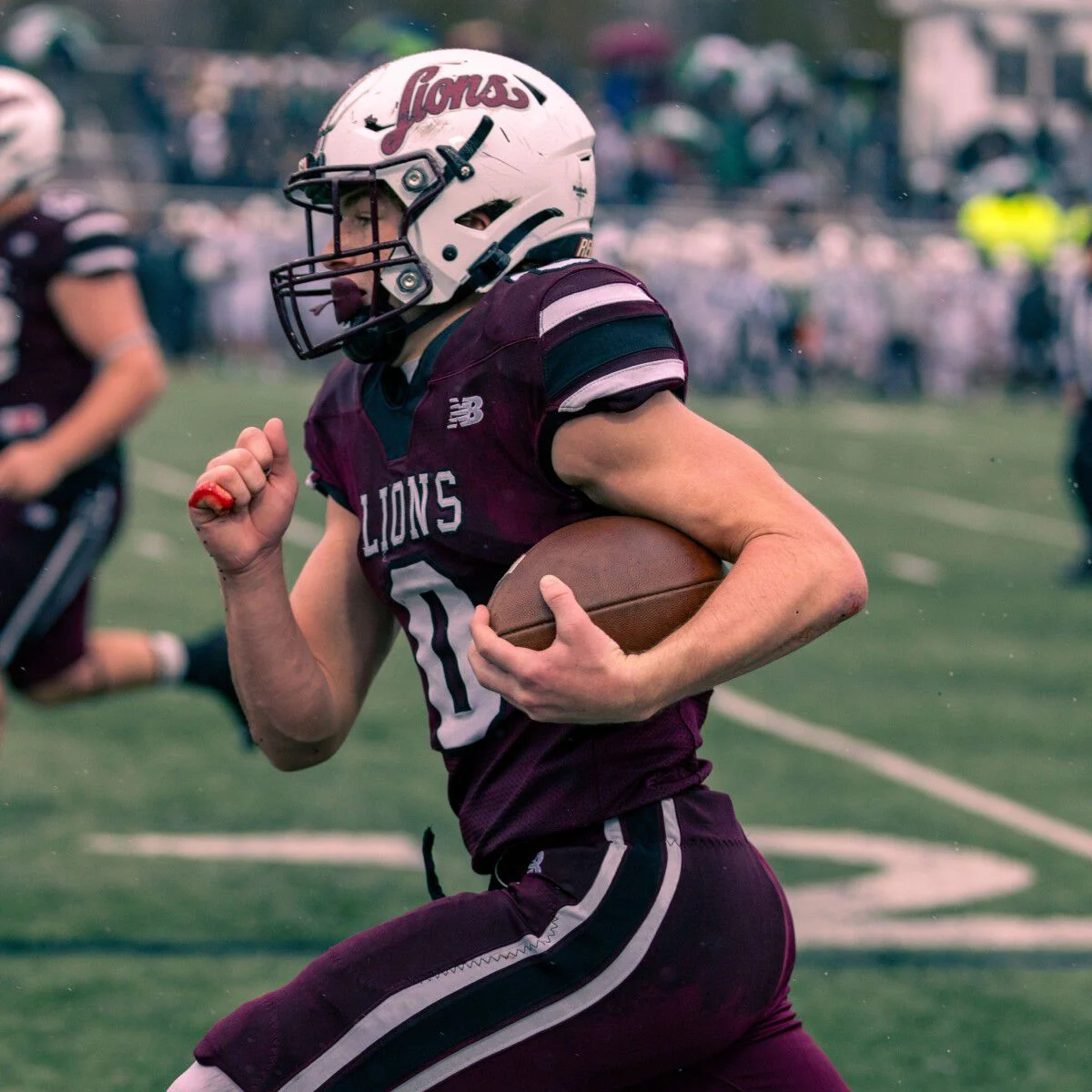 Young football athlete running with the ball on the field.
