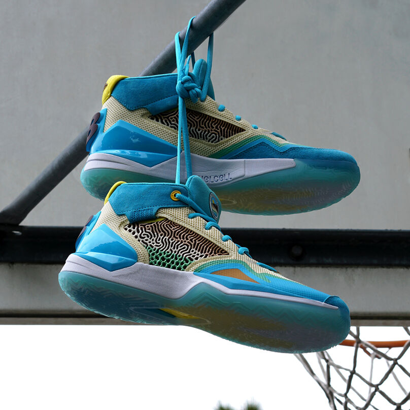 A pair of light blue Moreno Valley inspired KAWHI signature shoes hanging from their laces on the metal work behind the basketball hoop