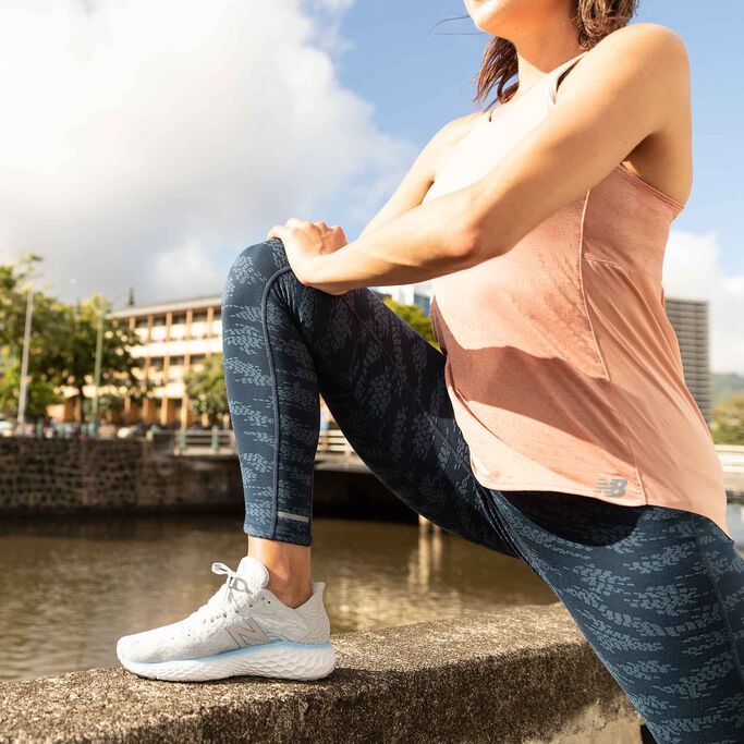 Runner stretching with foot propped on a concrete barrier