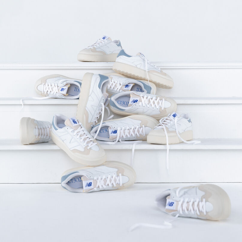 Plusieurs paires de chaussures CT302 blanches posées sur des escaliers blancs