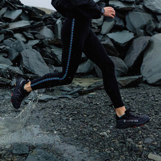 Woman in black tights running through water puddle