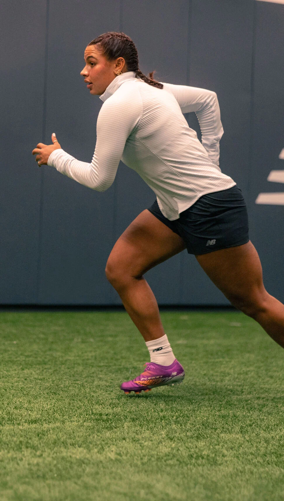 Young athlete running for a ball inside the training facility. 