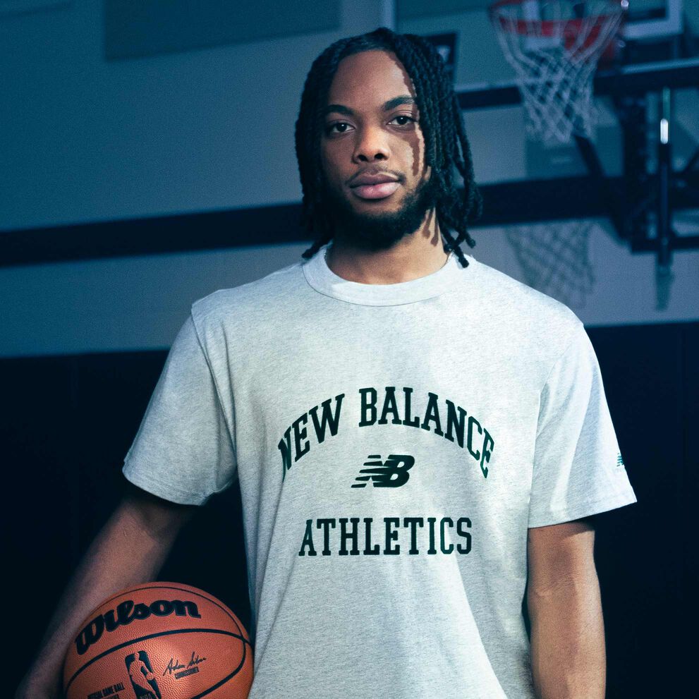 Darius Garland debout dans un gymnase tenant un ballon de basket.
