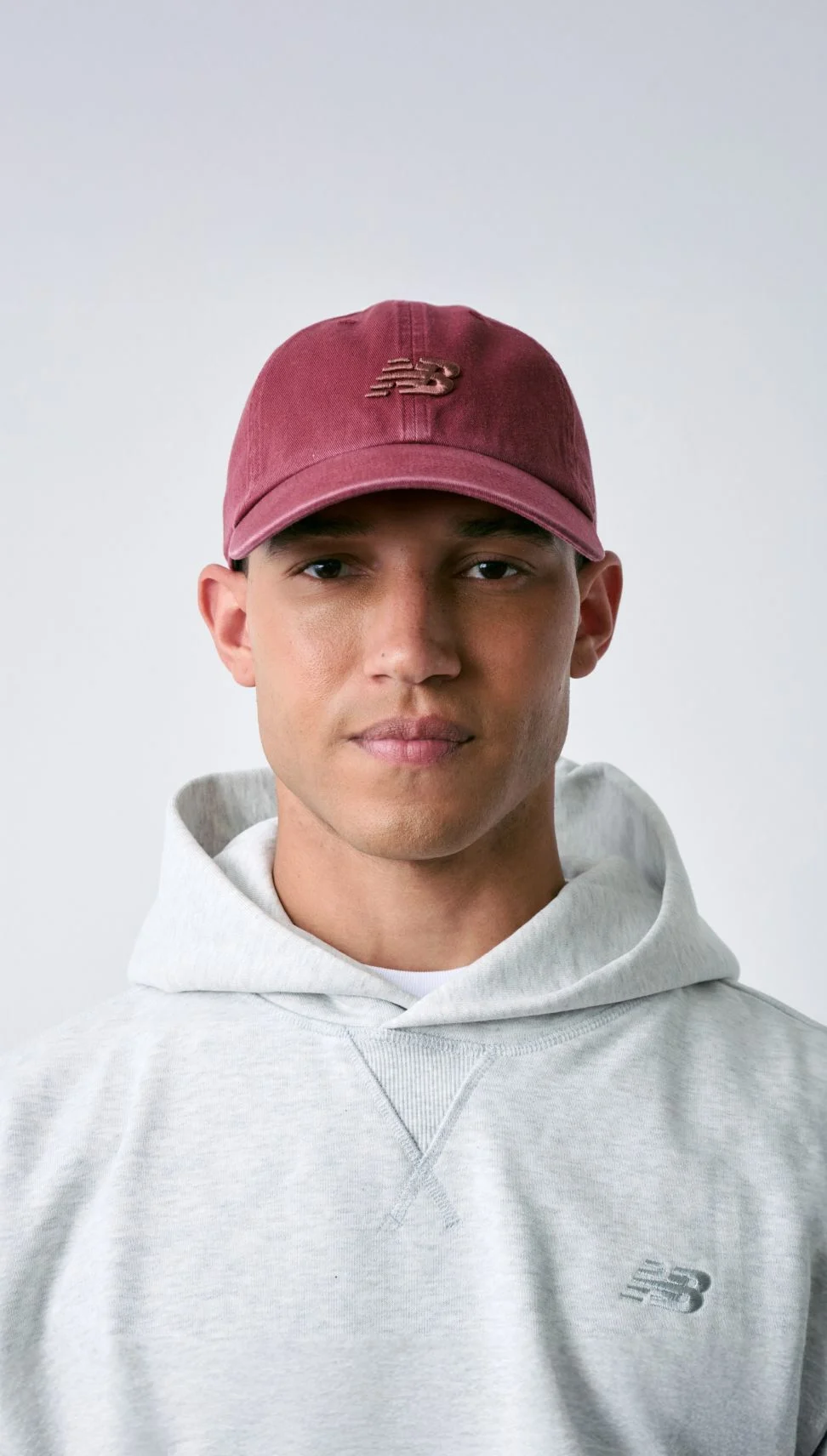 Man wearing New Balance hat standing against white wall