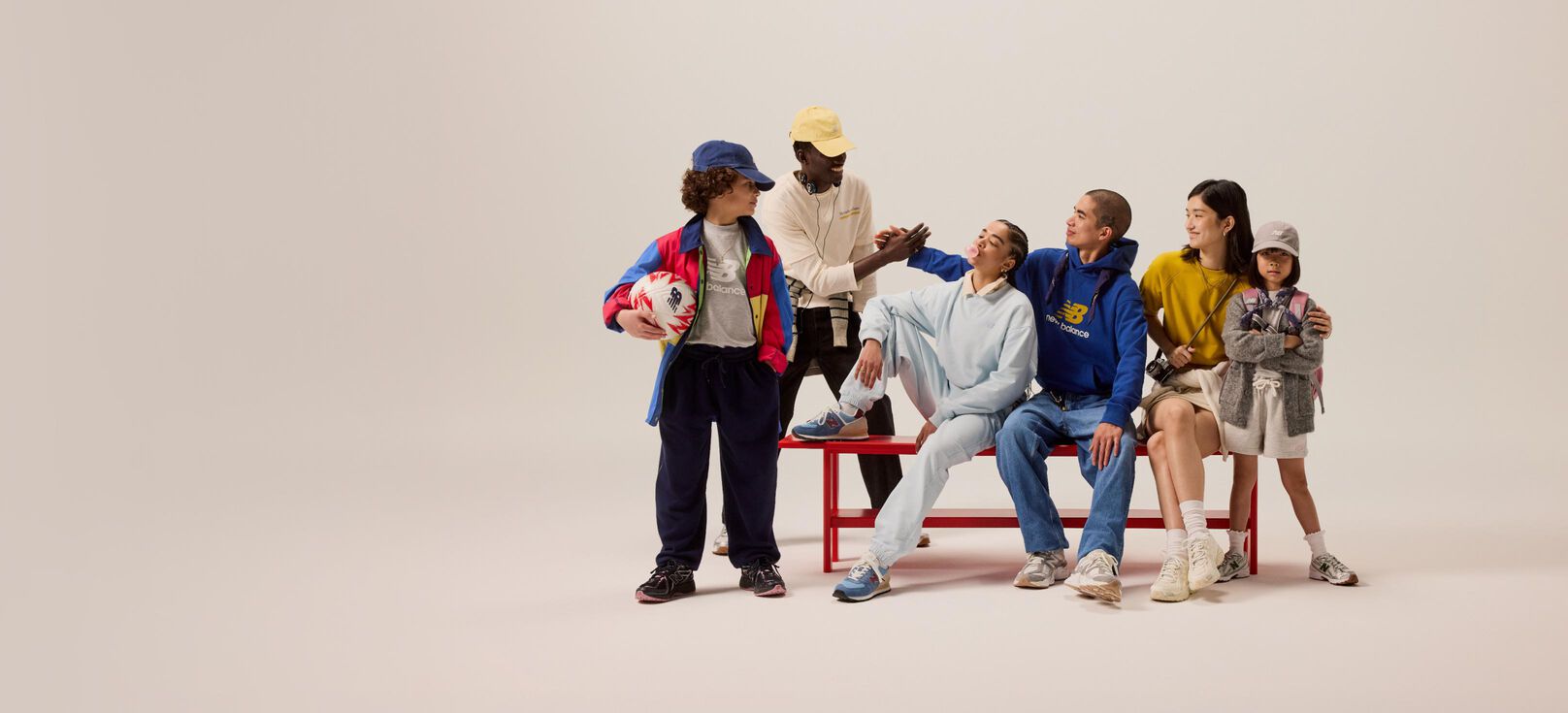 Groupe d'étudiants assis sur un banc rouge devant un fond beige. 