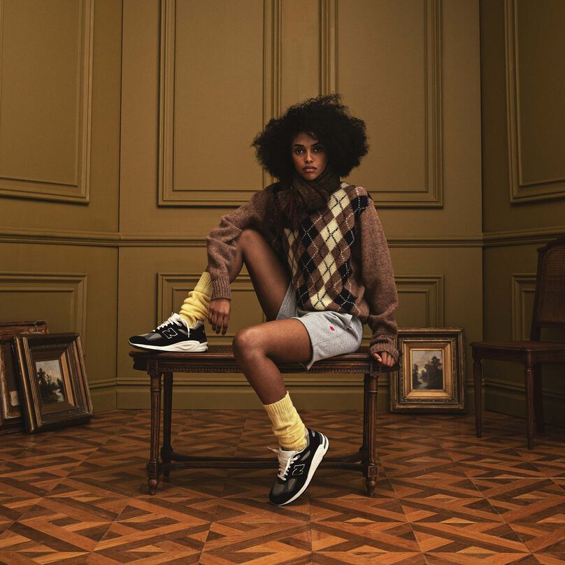 Une femme assise sur un banc dans un bel environnement intérieur portant des vêtements et des chaussures New Balance MADE in USA.
