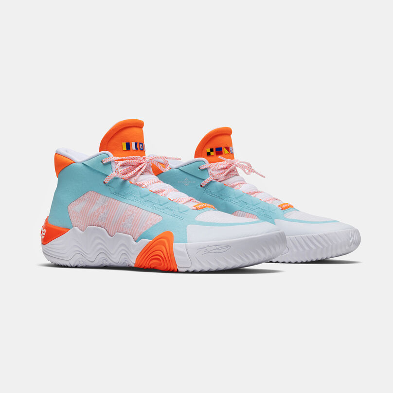 Pair of white and orange basketball shoes facing to the right on a grey background.