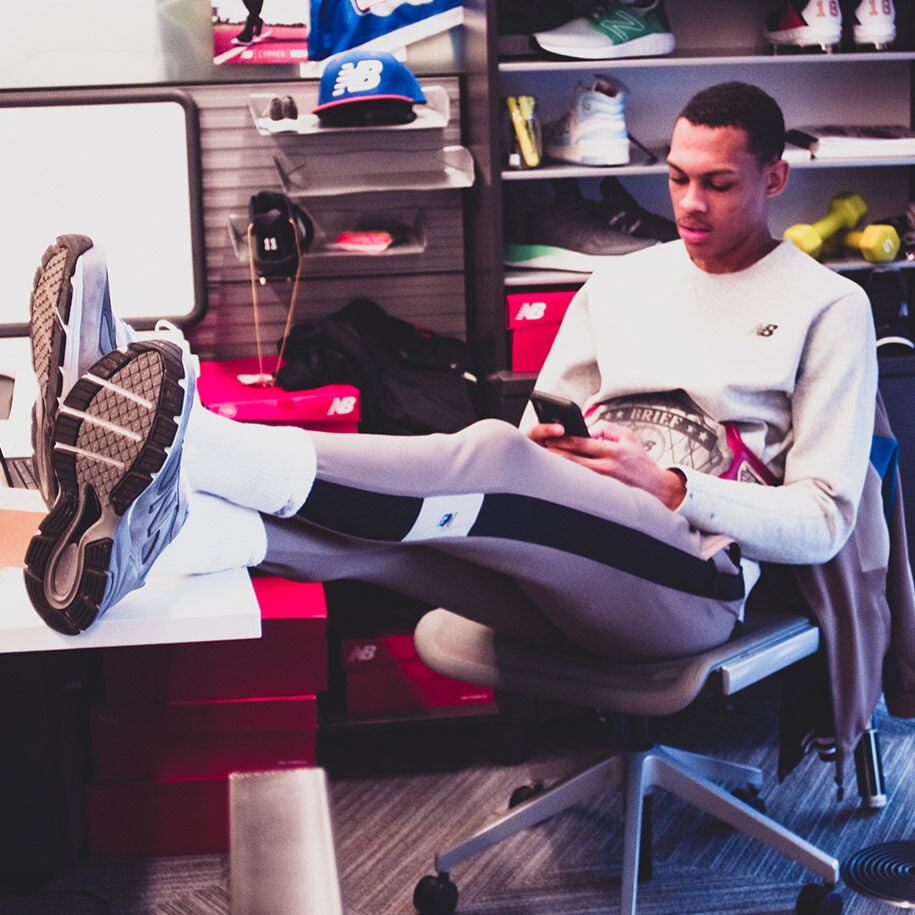 Lounging in his chair checking email on his phone.