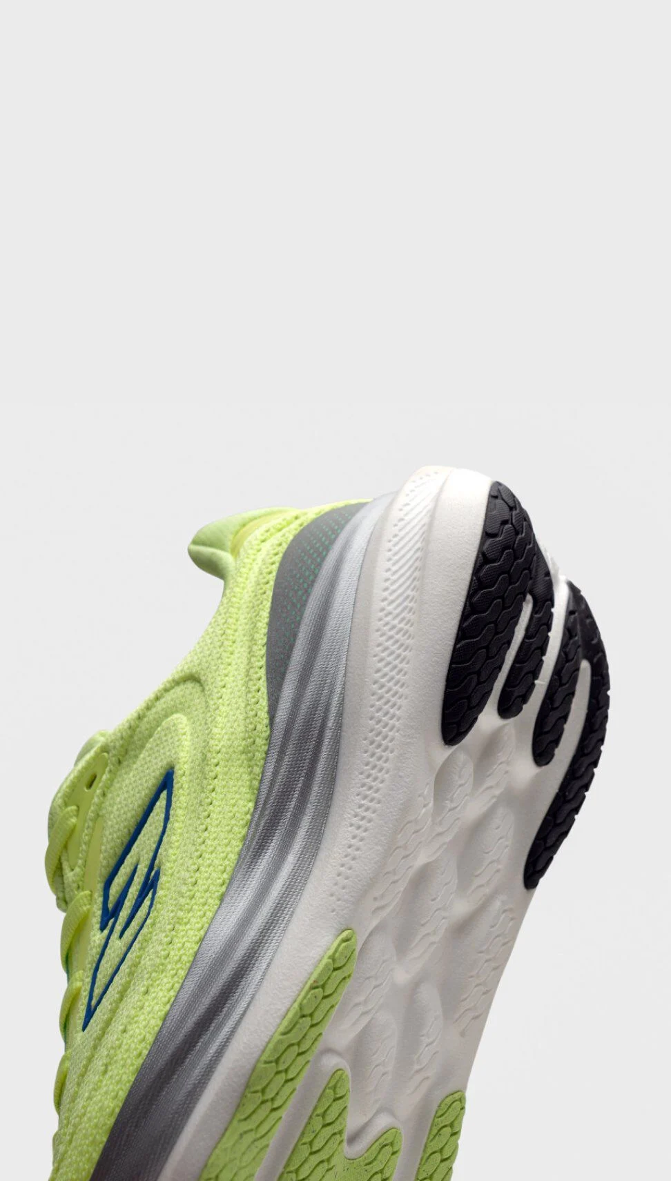 Gros plan sur le talon et la semelle d&rsquo;une chaussure de course New Balance jaune-vert vif, avec logo bleu, d&eacute;tails gris et semelle blanche dot&eacute;e d&rsquo;une bande de roulement noire.&nbsp;