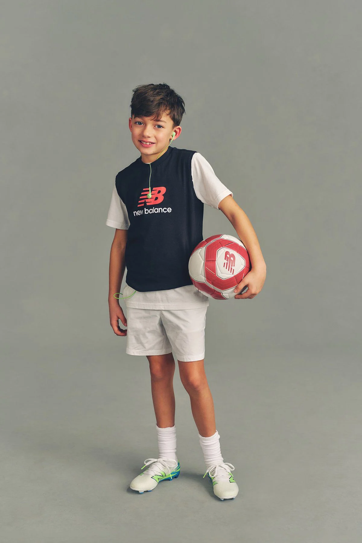Un enfant tenant un ballon de soccer devant un fond gris de studio.