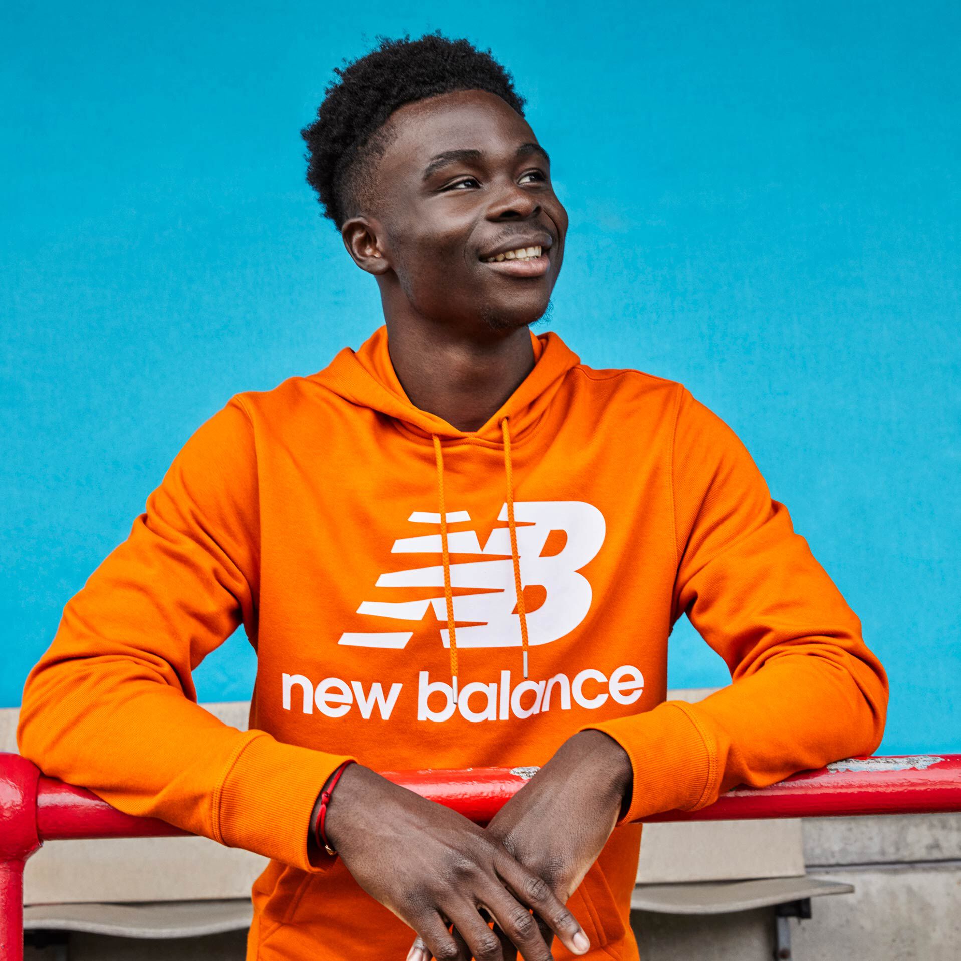 Photo de Bukayo Saka, cuisse découverte, souriant et penché sur une rampe