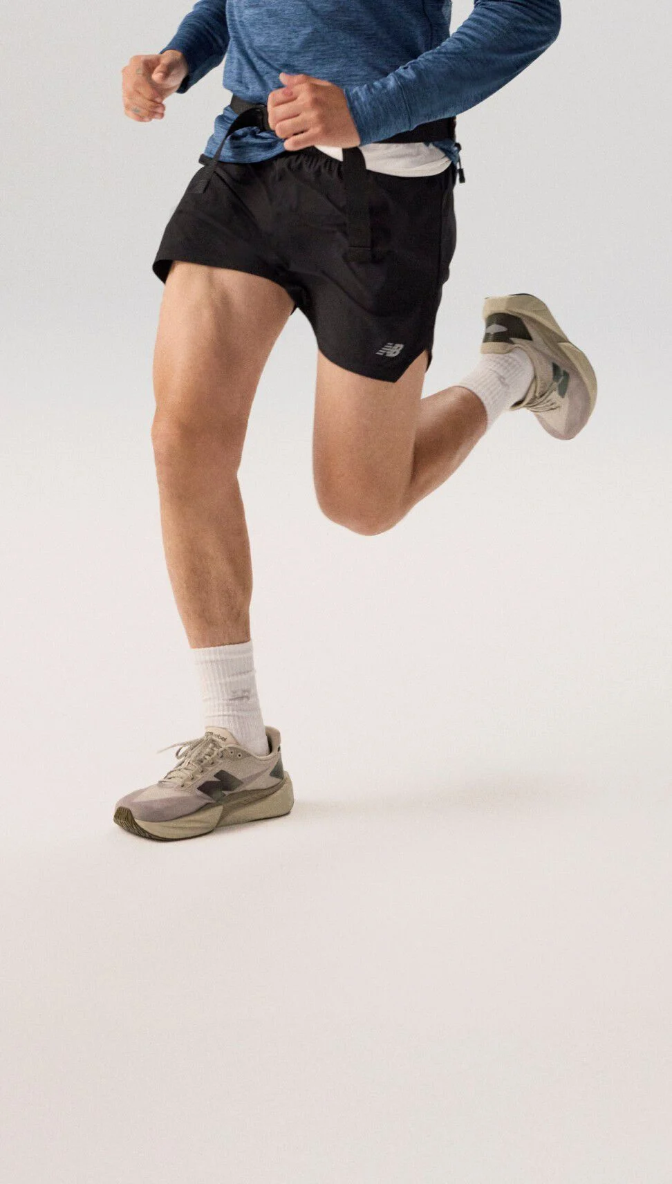 Jeune homme courant en hoodie bleu marine sur fond gris.