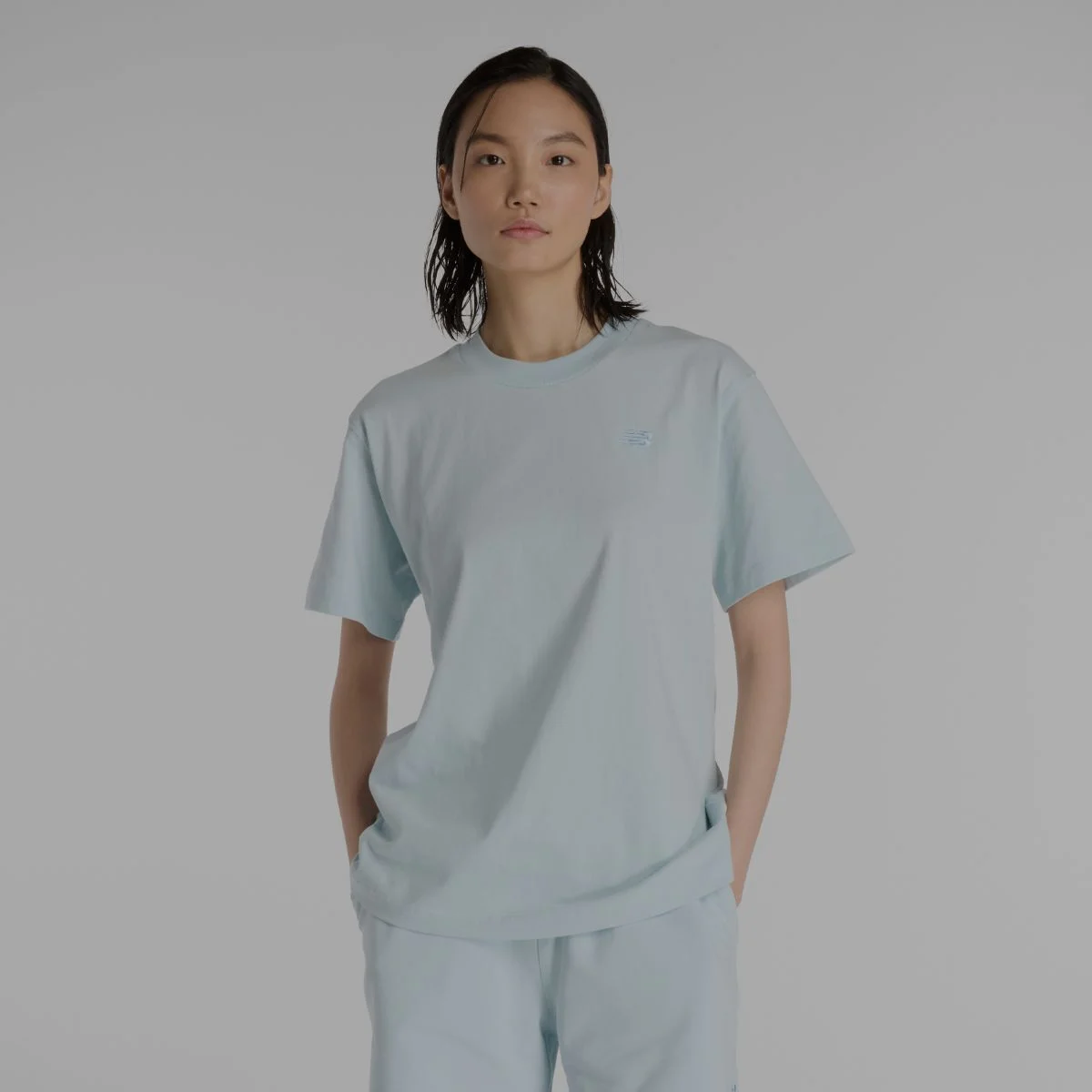 Une femme portant un t-shirt New Balance bleu clair.